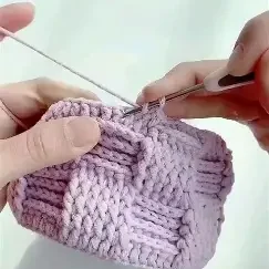 Shows someone crocheting a granny square with pink yarn